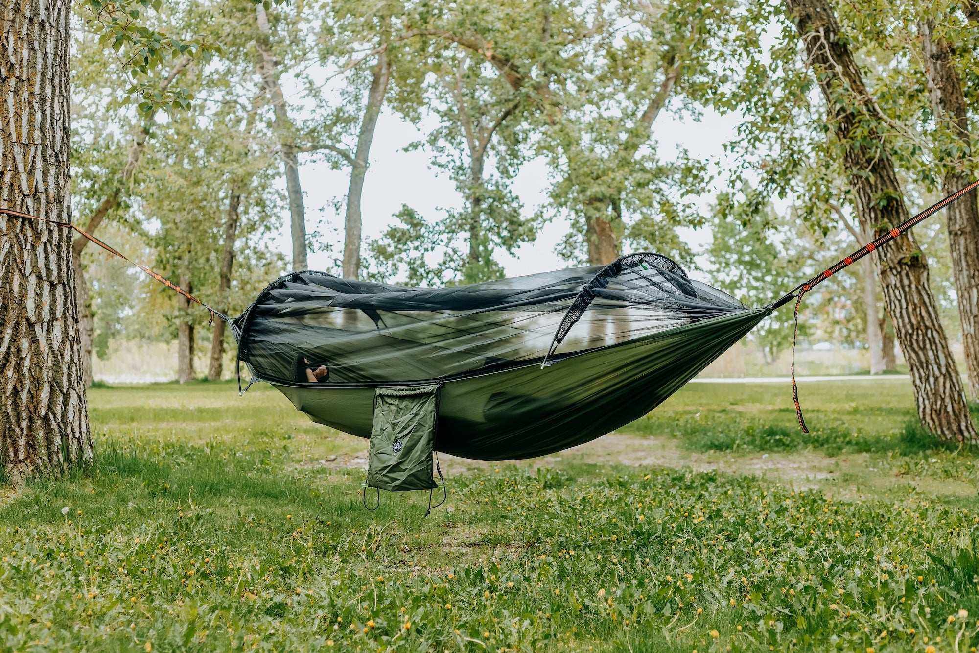 Lightweight hammock with mosquito net in a forest setting for outdoor comfort.